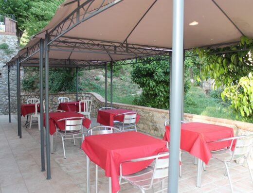 Tavoli all'aperto con tovaglie rosse sotto un gazebo presso Locanda Fosca Umbra, ideale per motociclisti in viaggio