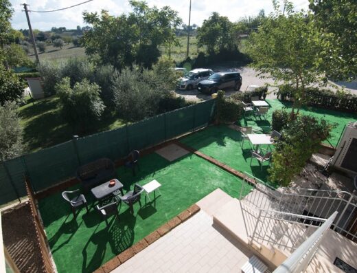 Locanda Olivi: Vista dall'alto del giardino con tavoli, sedie, prato verde sintetico e zona parcheggio auto. Ideale per relax e viaggi in moto.