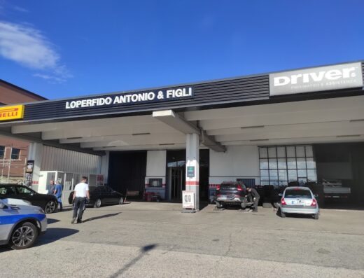 L'esterno dell'officina Loperfido Antonio & Figli, specializzata in pneumatici e assistenza per auto e moto, con auto in riparazione e personale al lavoro.
