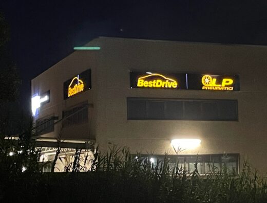 Insegne luminose di BestDrive e LP Pneumatici su un edificio, che indica un centro specializzato in pneumatici e servizi per auto e moto