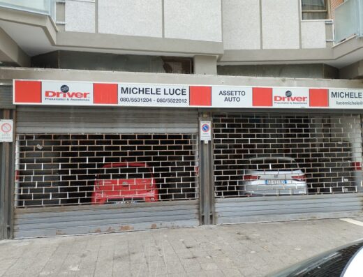 Luce Michele Driver Center Pirelli Bari: saracinesca chiusa di officina con insegna Driver Pneumatici & Assistenza e auto parcheggiate all'interno.