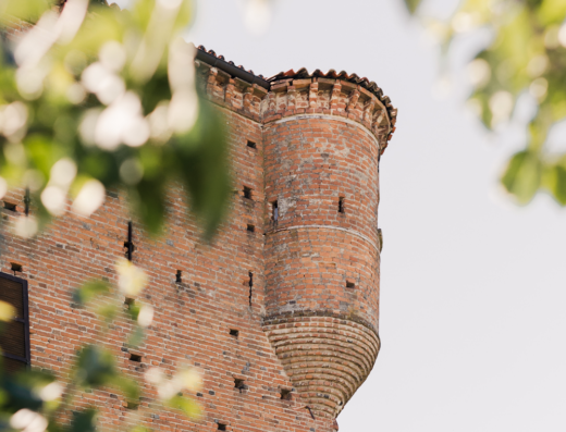 Ma che bel Castello: Dettaglio della torre in mattoni rossi dell'Azienda Agricola, con elementi architettonici medievali e vegetazione circostante.
