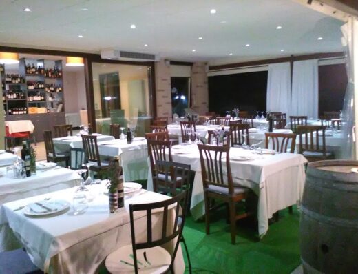 Interno accogliente della macelleria e bottega Azienda Agricola Bagalini, con tavoli apparecchiati e scaffali di vini.