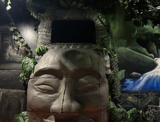 Dettaglio decorativo di MagicSuite Guest House Roma Vaticano con scultura di volto in pietra e vegetazione lussureggiante.