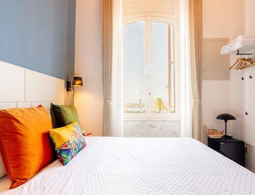 Camera luminosa di Magnini Rooms con letto matrimoniale, cuscini colorati e vista panoramica dalla finestra. Arredamento moderno e accogliente per un soggiorno confortevole.