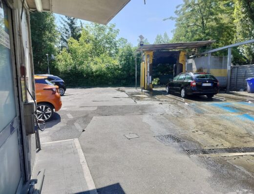 Autolavaggio Malik: auto nera in fase di lavaggio automatico. Servizi di pulizia auto professionali e autolavaggio self-service.