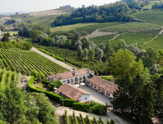 Vista aerea dell'Agriturismo Marcarini, immerso tra i vigneti delle Langhe, con edifici in stile rustico e curati spazi esterni.