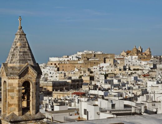 Vista panoramica di Ostuni, la Città Bianca in Puglia, con il campanile in pietra della Masseria Il Frantoio in primo piano.