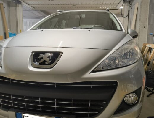 Primo piano di una Peugeot grigia in garage per i servizi di Mastellotto Igor Autolavaggio, dettaglio del frontale e della targa.