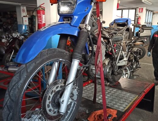 Mautone Moto: Dettaglio di una moto Yamaha blu su un ponte sollevatore in officina, ideale per riparazioni e manutenzione moto.