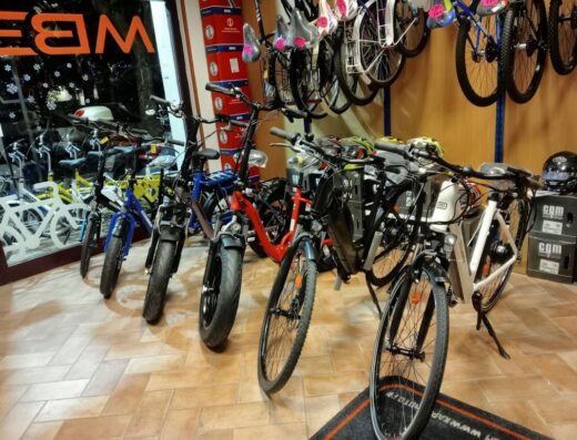 Esposizione di biciclette elettriche e tradizionali nel negozio MB3 a Fiumicino, con vari modelli e accessori per il cicloturismo.