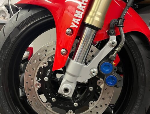 Dettaglio della ruota anteriore di una moto Yamaha, con parafango rosso, pinze freno blu e pneumatico Pirelli Diablo Rosso.