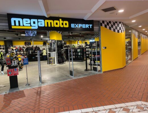 Ingresso del negozio Mega Moto Expert con moto gialla esposta, abbigliamento tecnico e accessori per motociclisti.