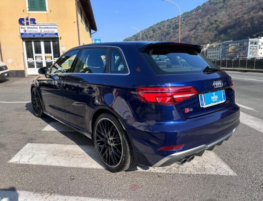 Auto Audi S3 blu scuro parcheggiata su strada cittadina con edificio in background. Servizio di autolavaggio e detailing MG per auto di lusso.