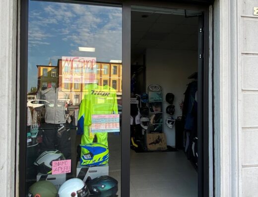 Negozio di moto MG SHOP a Novara, Italia. Vetrina con caschi, abbigliamento tecnico e accessori per motociclisti e viaggiatori.