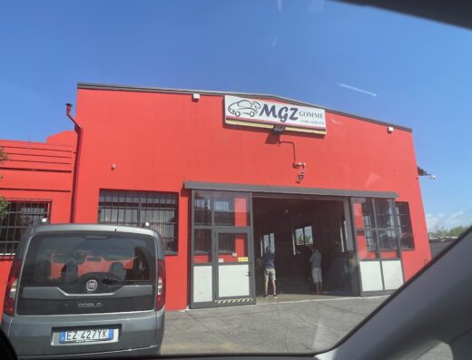 Mgz Gomme a Manerba del Garda, gommista specializzato nella riparazione e sostituzione di pneumatici per auto e moto, con insegna ben visibile e furgone Fiat parcheggiato.