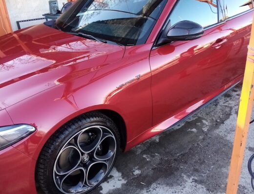 Primo piano di un'Alfa Romeo Giulia rossa appena lavata presso MIA Autolavaggio, che mostra la brillantezza della carrozzeria e dei cerchi in lega.