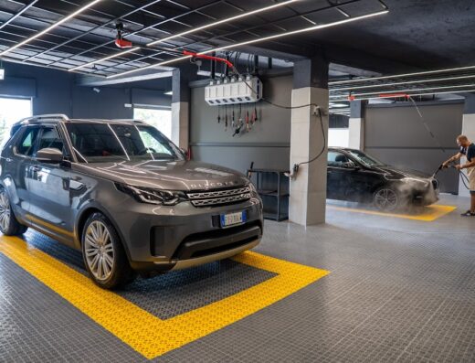 Autolavaggio Mid: SUV grigio e auto nera in fase di lavaggio con idropulitrice professionale. Servizi di pulizia auto e cura dei dettagli.