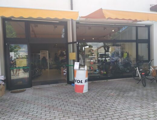 Miki Moto snc storefront featuring motorcycles, accessories, and gear displayed inside. A Repsol branded barrel stands outside the entrance.