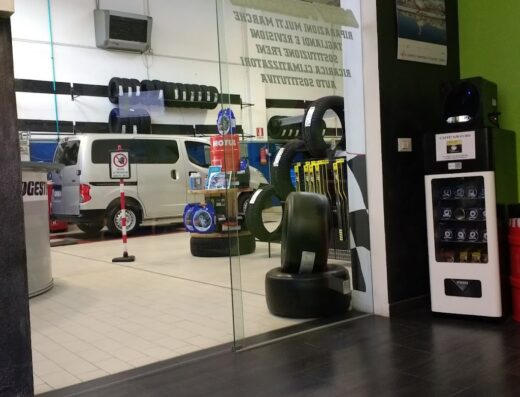 Interno dell'officina Miky Pneumatici di Pugliese Michele, con furgone, scaffali di pneumatici, e distributore automatico di bevande.