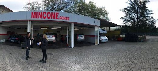 Mincone Gomme S.N.C.: Panorama dell'officina con clienti, auto in riparazione e vasto piazzale pavimentato. Servizi professionali per pneumatici e manutenzione auto.