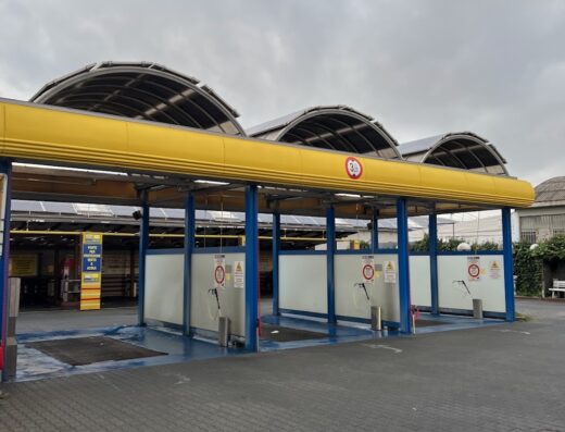 A motorcycle washing station with three bays, featuring yellow roofing and blue supports, ready for cleaning bikes and accessories.