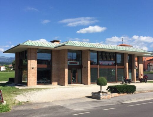 Mohave Motor Co. srls: edificio moderno in Italia con moto esposte, vetrine ampie e cielo azzurro. Servizi e vendita di moto.