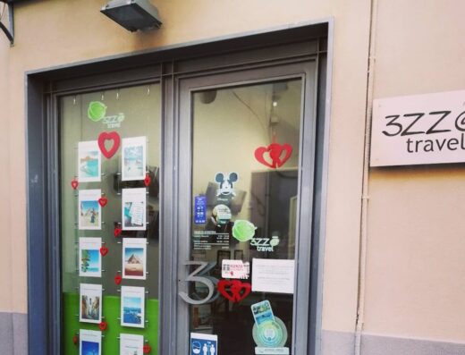 Ingresso dell'agenzia viaggi Mondo 3zz@Travel con vetrina decorata con cuori rossi e immagini di destinazioni turistiche.