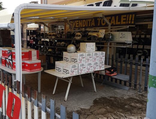 Esposizione esterna di Mondomoto S.R.L. con caschi da moto in vendita totale, accessori e ricambi visibili. Offerte speciali per motociclisti.