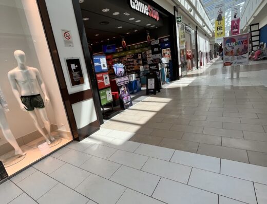 Ingresso del negozio GameStop all'interno del Mondovicino Outlet Village, con vetrine illuminate e segnaletica ben visibile.