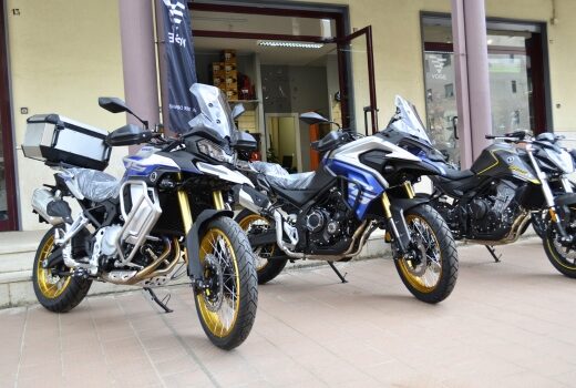 Moto e bici Matera: Tre motociclette, due da turismo blu e bianche con cerchi dorati e una moto da strada nera e gialla, parcheggiate all'aperto.