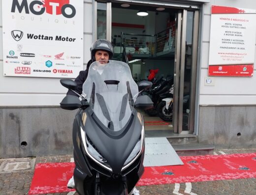 Un uomo su uno scooter Benelli di fronte a Moto Boutique S.R.L., concessionario di moto CFMOTO, VOGE, Benelli, Peugeot e Wottan Motor. Vetrina di vendita e noleggio moto, scooter e accessori.