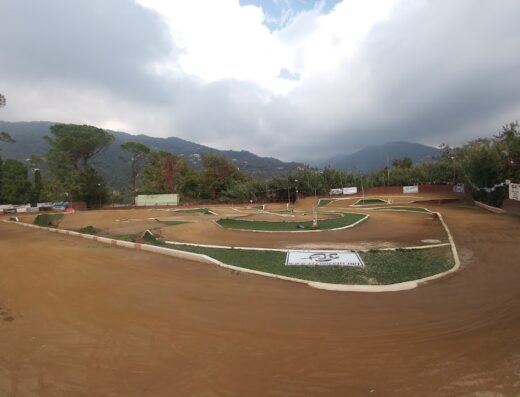 Vista panoramica del circuito di motocross del Moto Club Rapallo 'A.Olivari', con pista in terra battuta, ostacoli e vegetazione sullo sfondo.