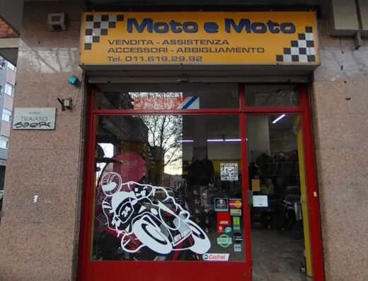 Foto del negozio Moto e Moto a Torino, specializzato in vendita, assistenza, accessori e abbigliamento per motociclisti. Vetrina con adesivo moto e marchi come Castrol e Askoll.