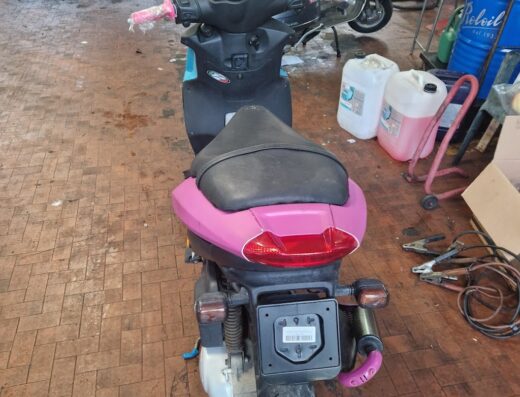 Moto Italia: Scooter customizzato rosa e azzurro in officina, accessori tuning, dettaglio del posteriore, marketplace moto usate.