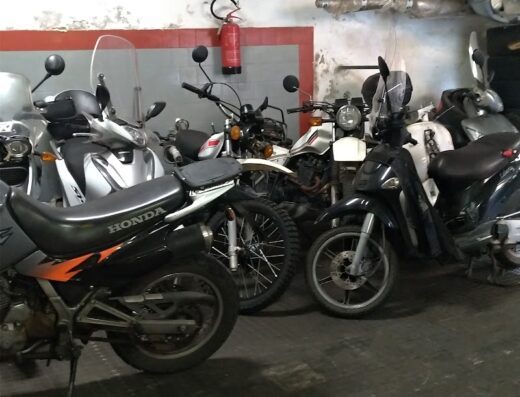 Garage with several motorcycles, including a black Honda, parked inside, near a Castrol banner and a fire extinguisher. Moto Mariani repair shop.