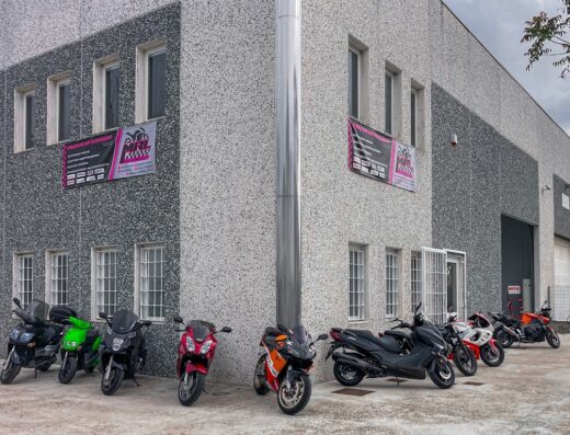 Diverse motociclette parcheggiate di fronte al Moto Racing Lab, con insegne che pubblicizzano servizi di officina e riparazione moto.