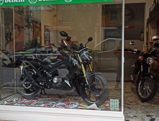 Moto Benelli esposta in vetrina presso Moto Service MG: dettaglio di una motocicletta nera con sospensioni dorate, ideale per viaggi e appassionati del marchio Benelli.