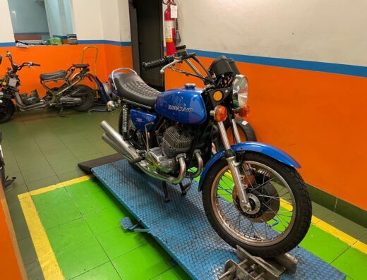 Moto Tre Erre: Kawasaki 750 H2 Mach IV blu su piattaforma elevatrice in officina, dettaglio del motociclo classico per appassionati e collezionisti.