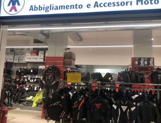 Negozio di motoabbigliamento con vasta scelta di giacche, accessori moto e caschi. Vetrina illuminata che mostra le ultime offerte.