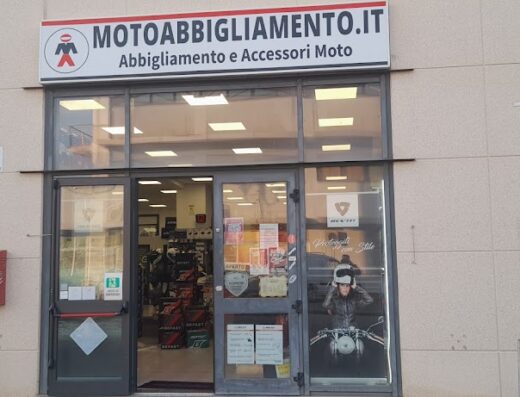 Foto della facciata del negozio Motoabbigliamento.it, specializzato in abbigliamento e accessori moto. Si vedono la vetrina e l'ingresso del negozio.