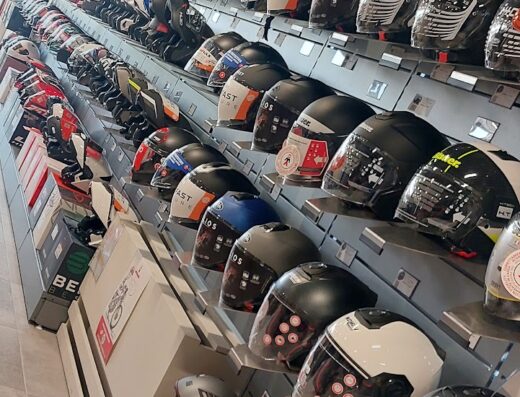 Ampia esposizione di caschi da moto di diverse marche come Nolan e Shark in un negozio di motoabbigliamento.