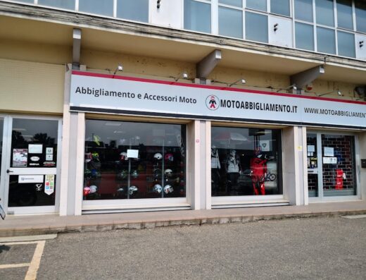 Negozio di motoabbigliamento con vetrine che espongono caschi, accessori e abbigliamento tecnico per motociclisti.
