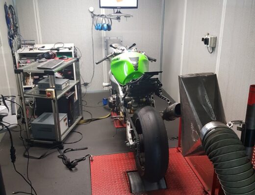 Motofficina Magnoni: A green Kawasaki motorcycle is on a dynamometer for performance testing and diagnostics, with associated equipment and monitor visible.