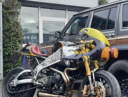 Moto customizzata parcheggiata di fronte a un'officina autorizzata, con dettaglio della carrozzeria e degli accessori, un'esperienza di viaggio unica.