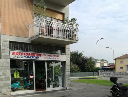 Motoforniture Bergamasche: negozio di accessori e ricambi moto. In vetrina, scooter azzurro e abbigliamento tecnico. Servizi di officina e vendita online.