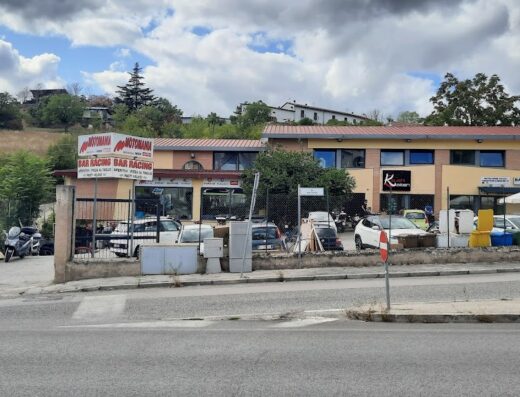 Motomania di Risdonne Matteo: Esterno del negozio con insegna "Motomania BAR RACING", moto parcheggiate e auto. Servizi e accessori per motociclisti.