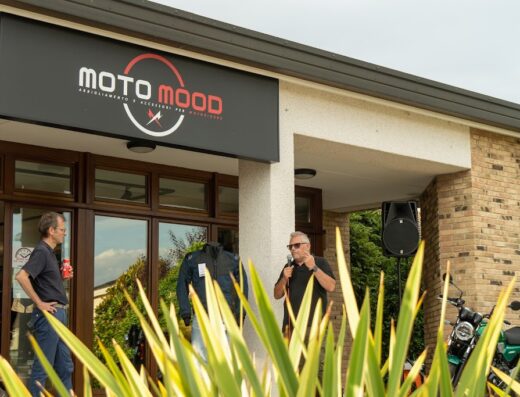 MotoMood, negozio di abbigliamento e accessori moto: inaugurazione con persone, giacca da moto esposta e moto parcheggiata.