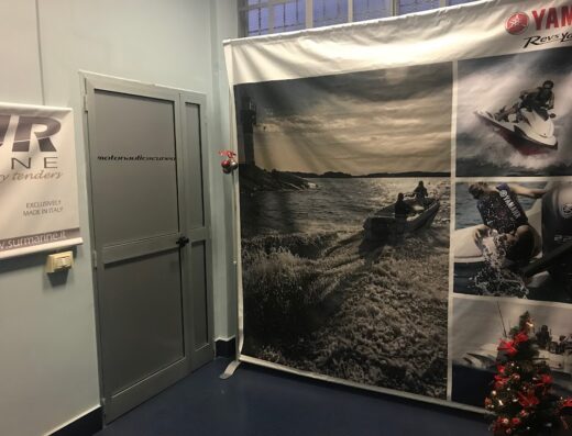 Interno di Motonautica Cuneo con banner Yamaha che mostra moto d'acqua e barche, porta con logo e albero di Natale, focus su accessori e servizi nautici.