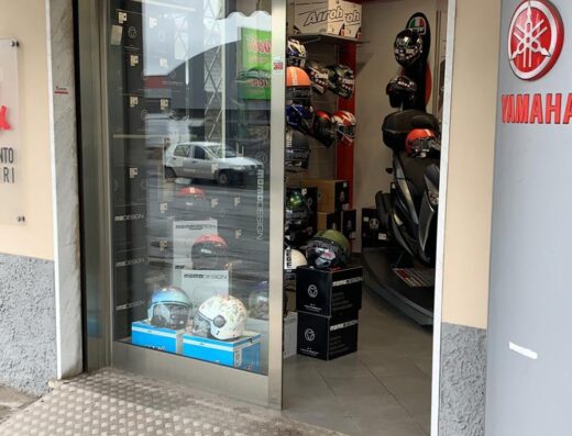 Negozio di accessori e ricambi moto Motoracing Calamari, con caschi Airoh e Momo Design in vetrina e scooter Yamaha all'interno.